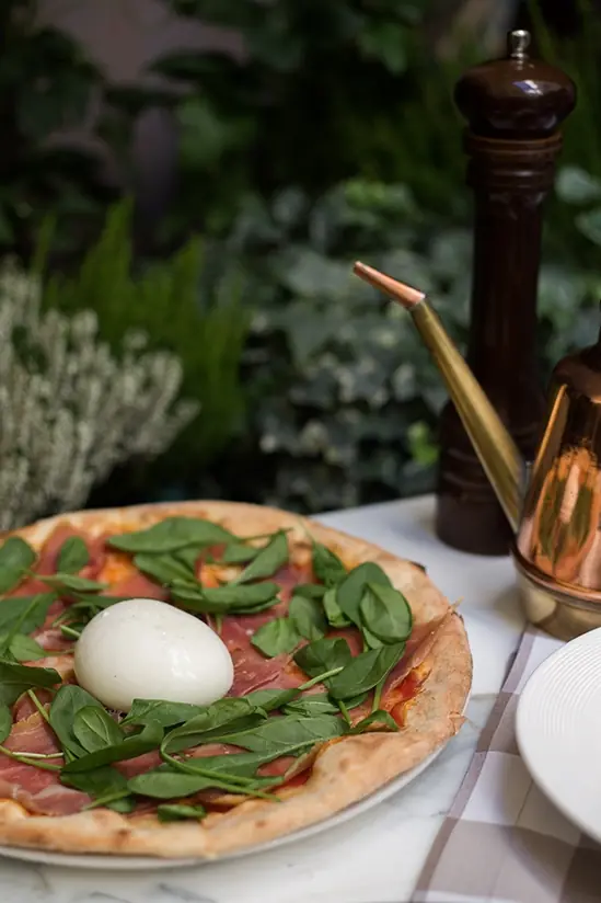 Pizza z burratą i szynką parmeńską podana na tarasie